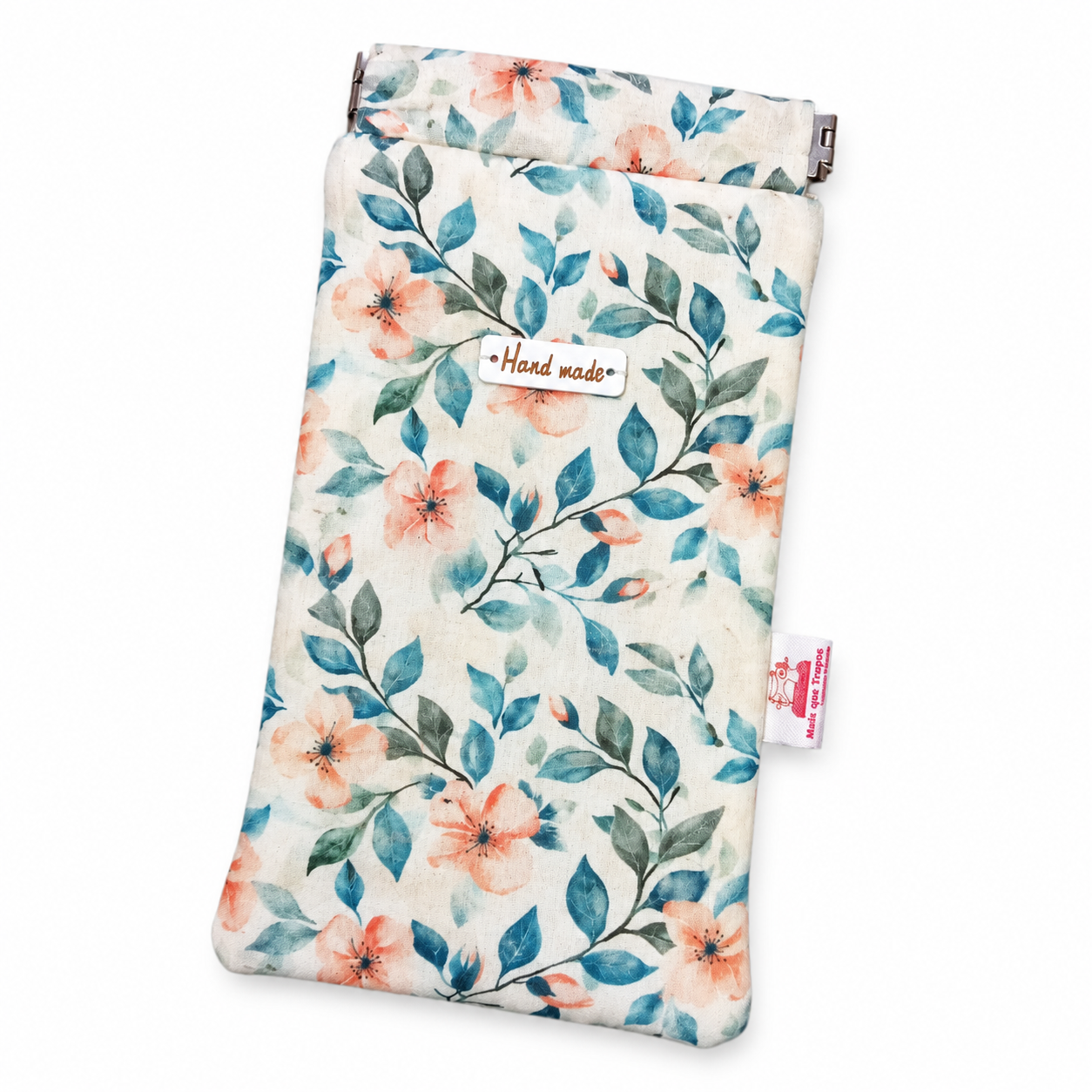 Bolsa artesanal de tecido com estampa floral azul, verde e laranja, etiqueta “Hand made” e fecho metálico.